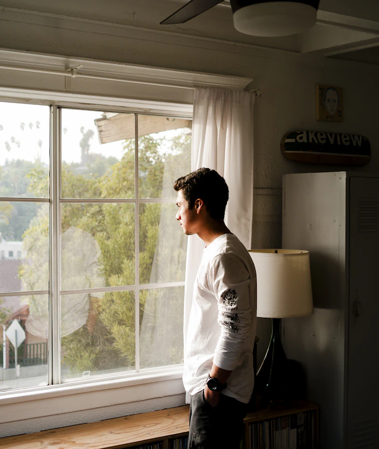 Someone standing at a window, with a moment to think